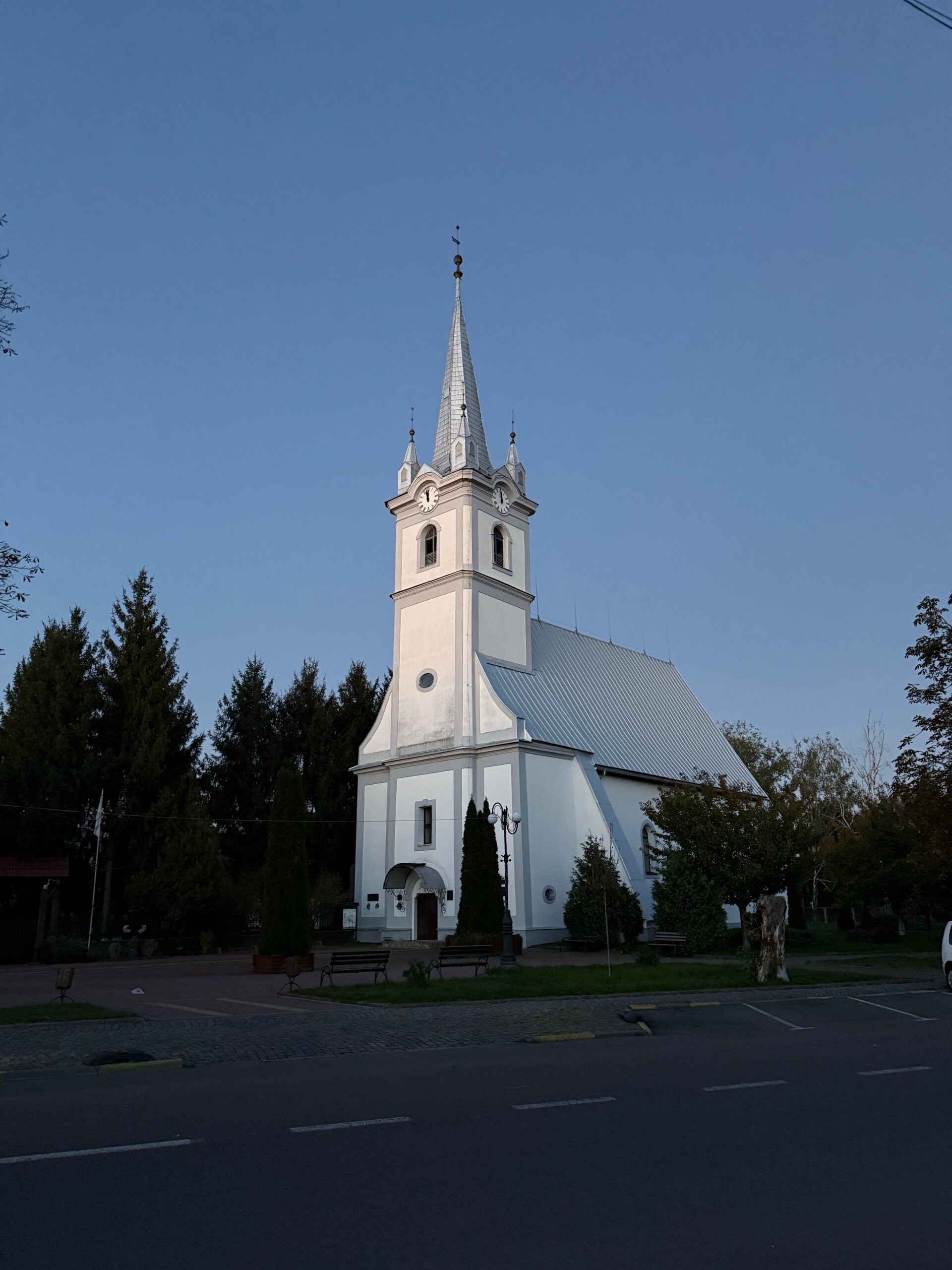 A white church with a tall steeple against a clear evening sky